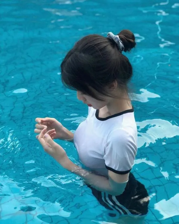 anh-gai-di-bien-che-mat-18 Cô gái trong nước xanh, tóc búi gọn, quay nghiêng mặt, da sáng nổi bật và khỏe khoắn.