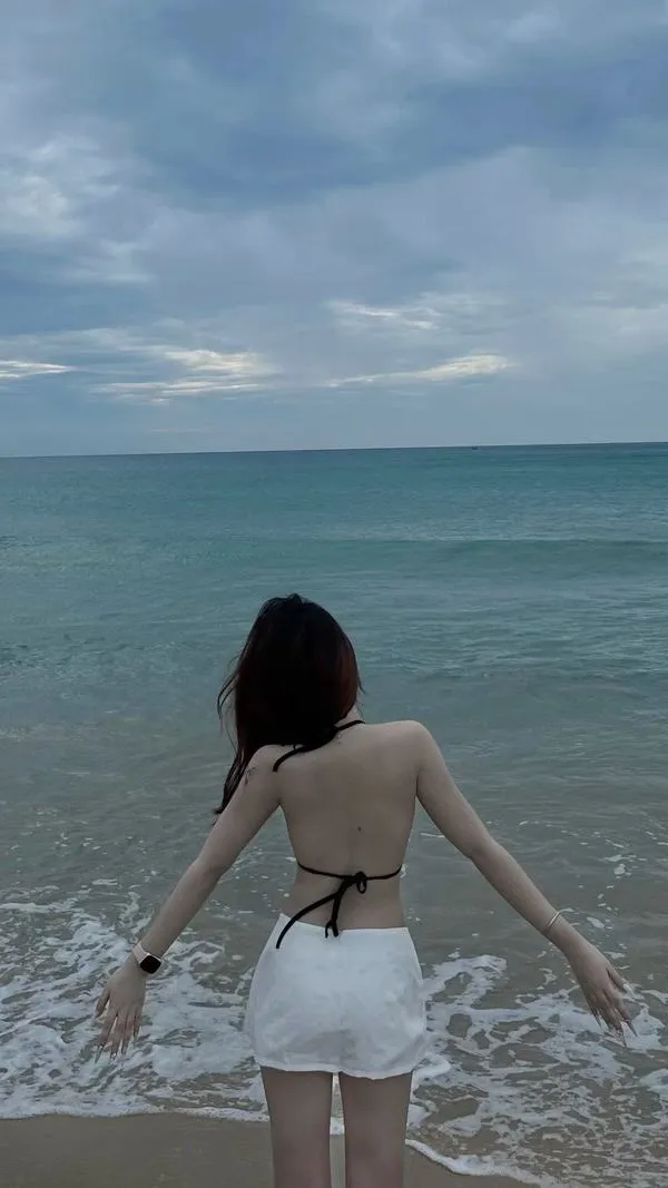 anh-gai-di-bien-che-mat-19 Nàng mặc đồ hở lưng, đứng sát mép nước, tóc dài, dáng mảnh và cuốn mắt.