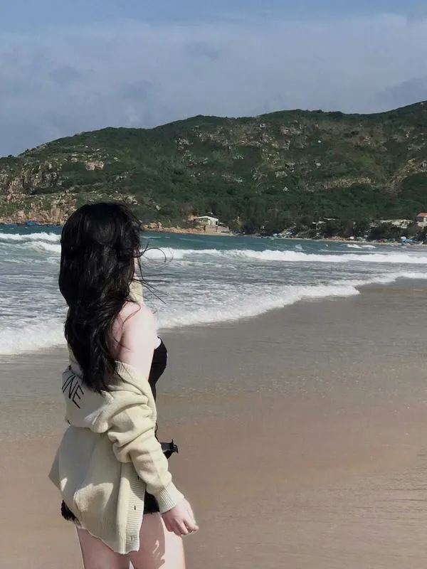 anh-gai-di-bien-che-mat-29 Nàng đứng trước biển xanh ngọc, váy sáng, tóc dài, ánh nhìn giấu sau bờ vai.